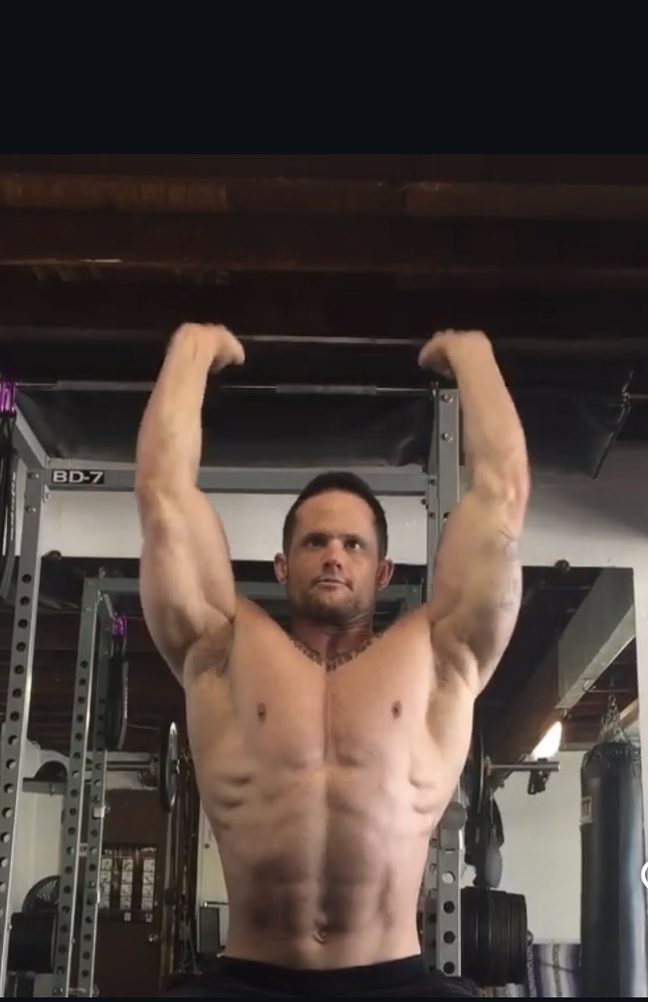 Chad Binkley with both arms raised overhead, gripping a pull-up bar