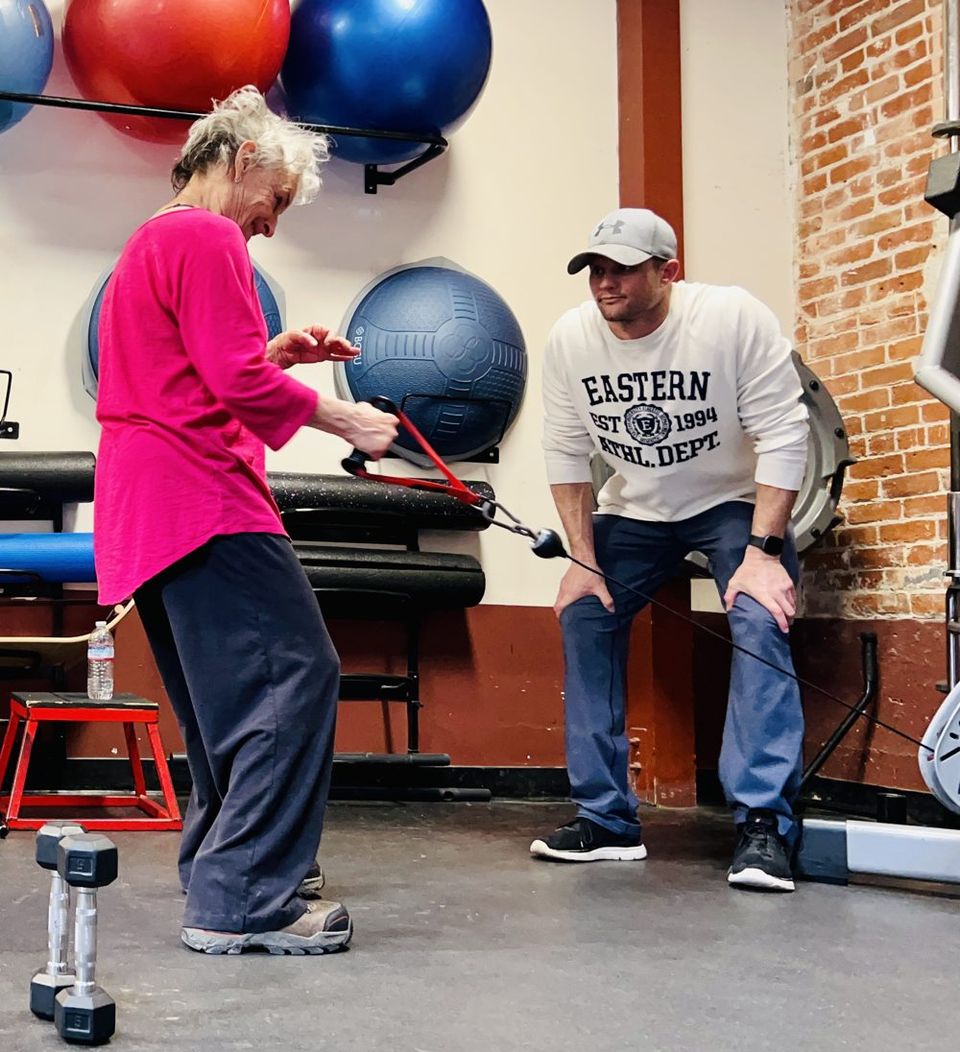 Chad Binkley leaning in to watch closely as a client performs a cable exercise in the gym